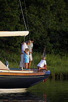 Family watches the shore from the back of a cruising yacht, Rhode Island.