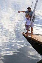 Father and son on the bow of a Friendship 40 cruising yacht, Rhode Island. Model released and property released.