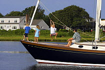 Young family playing the bow of a cruising yacht, Rhode Island.