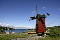 Windmill on the coast with moored yachts below, Gullkrona, Finnish Archipelago, Finland.