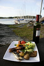 BBQ meal and bottle of wine in a harbour, Finnish Archipelago, Finland.