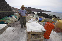 Local man salting fish to preserve them in a fishing village on Isla Coyote, Mexico, 2006.