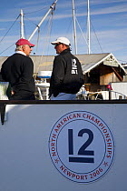 Two men talking on board a yacht anchored in the harbour ready for racing in the 12m North American Championships 2006, Newport, Rhode Island, USA.