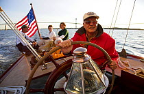 Helmsman and passengers during an evening charter onboard 12m yacht "Gleam" sailing in Narragansett Bay off Newport, Rhode Island, USA, 2006.