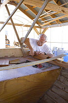 A man works on the stern of a wooden boat in a boat yard, Charleston, South Carolina, September 2006.