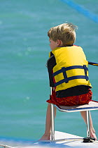 Young boy sitting on the bow seat on the deck of a catamaran, British Virgin Islands, Caribbean, December, 2006.