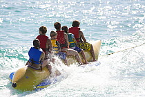 Children being towed along on a banana boat, British Virgin Islands, Caribbean. December 2006.