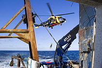 Winchman being lowered from a helicopter during a training excercise with a fishing vessel on the North Sea.