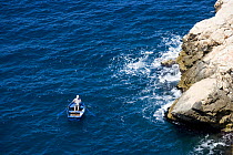 Man rowing a small boat near the cliffs, Dubrovnik, Croatia.
