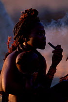 Himba woman in traditional dress smoking pipe. Kaokoland Namibia