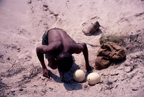 Kalahari bushman drinking water from buried Ostrich egg. Botswan