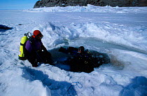 Doug Allan and Andrew Taqtu prepare to dive through ice hole Arctic Bay Nunavut Canada