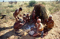 Kalahari bushmen family round fire outside hut. Botswana 1992