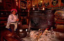 Tibetan ethnic minority woman cooks on traditional stove in house. Zhongdian, Yunnan, China