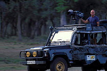 Simon King presenter of Big Cat Diary in vehicle with film camera Masai Mara NR Kenya 2000