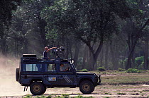 Simon King presenter of Big Cat Diary in vehicle with film camera Masai Mara NR Kenya 2000