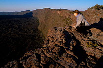 Woman peers over edge of volcano crater La Fournaise La Reunion Indian ocean