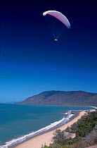 Paraglider flies over beach Queensland Australia